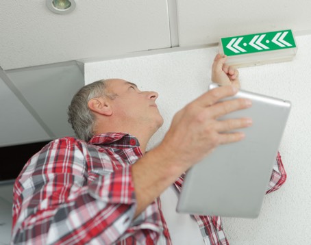 man-holding-tablet-checking-emergency-exit-sign-P3BU4AP